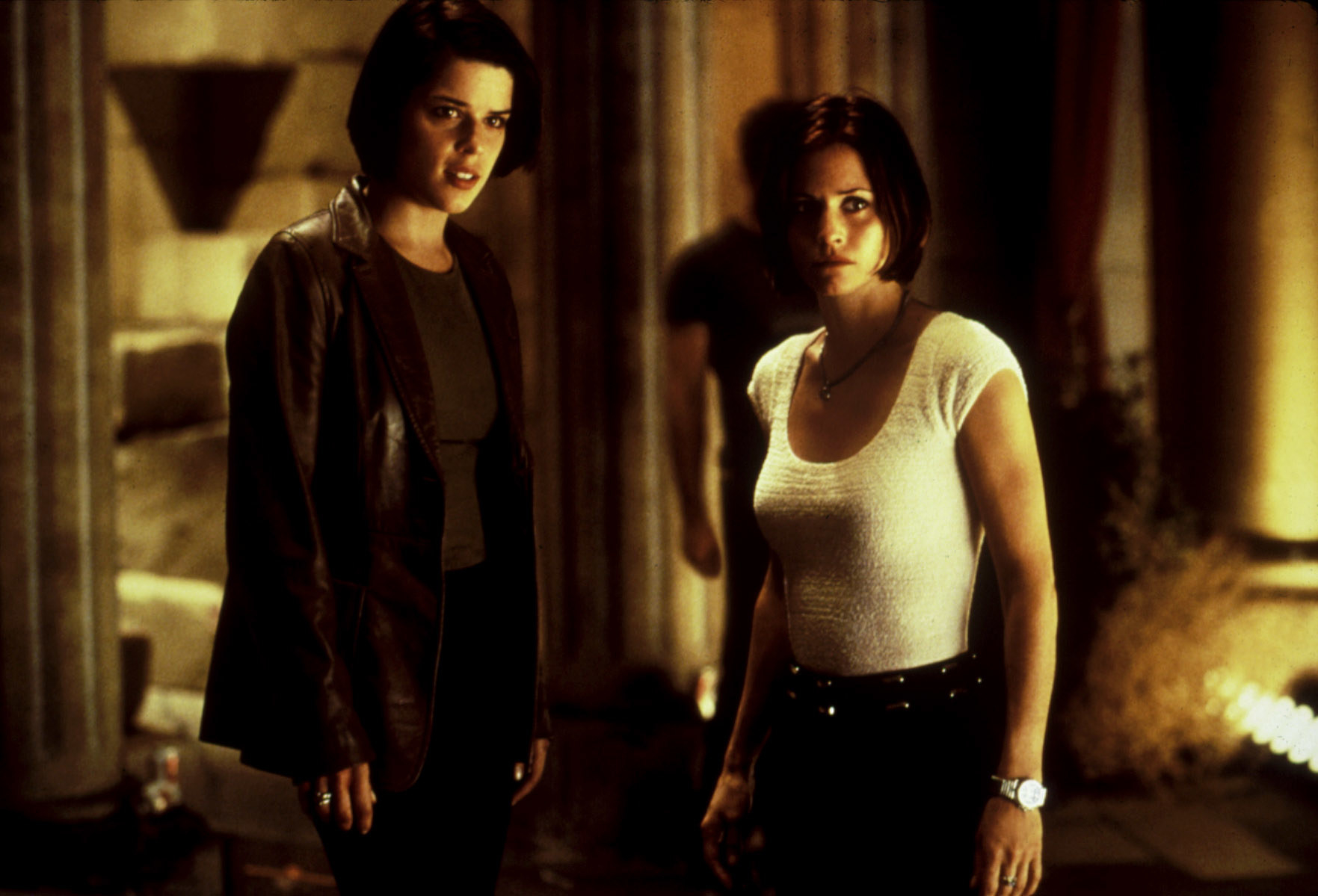 Courteney and Neve stand together in the film and look at something with concern