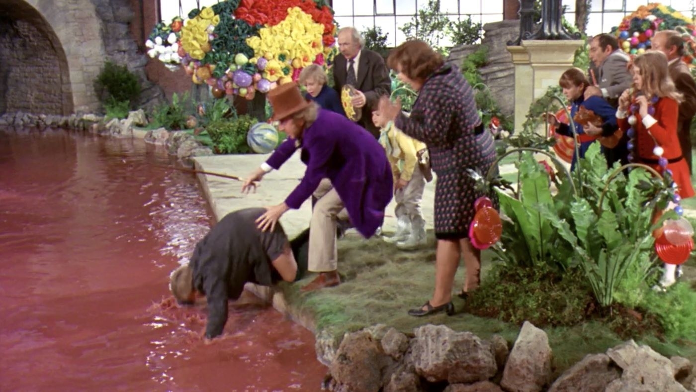 Augustus Gloop falling into the chocolate river as the rest of the tour look on, shocked