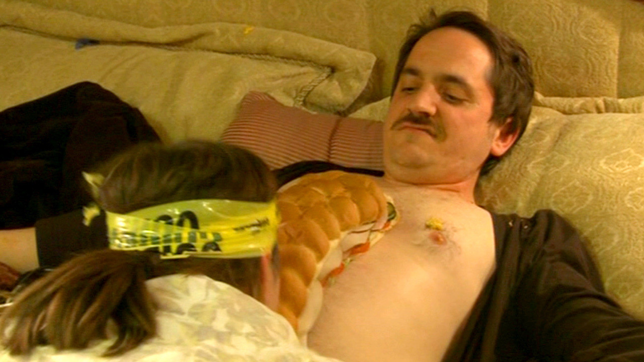Melissa McCarthy as Megan eating a huge sandwich off the bare chest of Ben Falcone