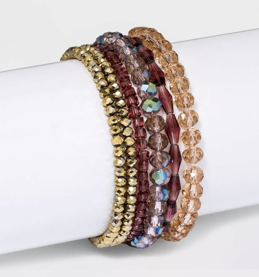 a set of gold, red, and beige beaded bracelets
