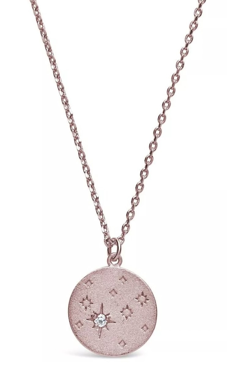 a rose gold pendant necklace with a constellation and a gem in one of the stars