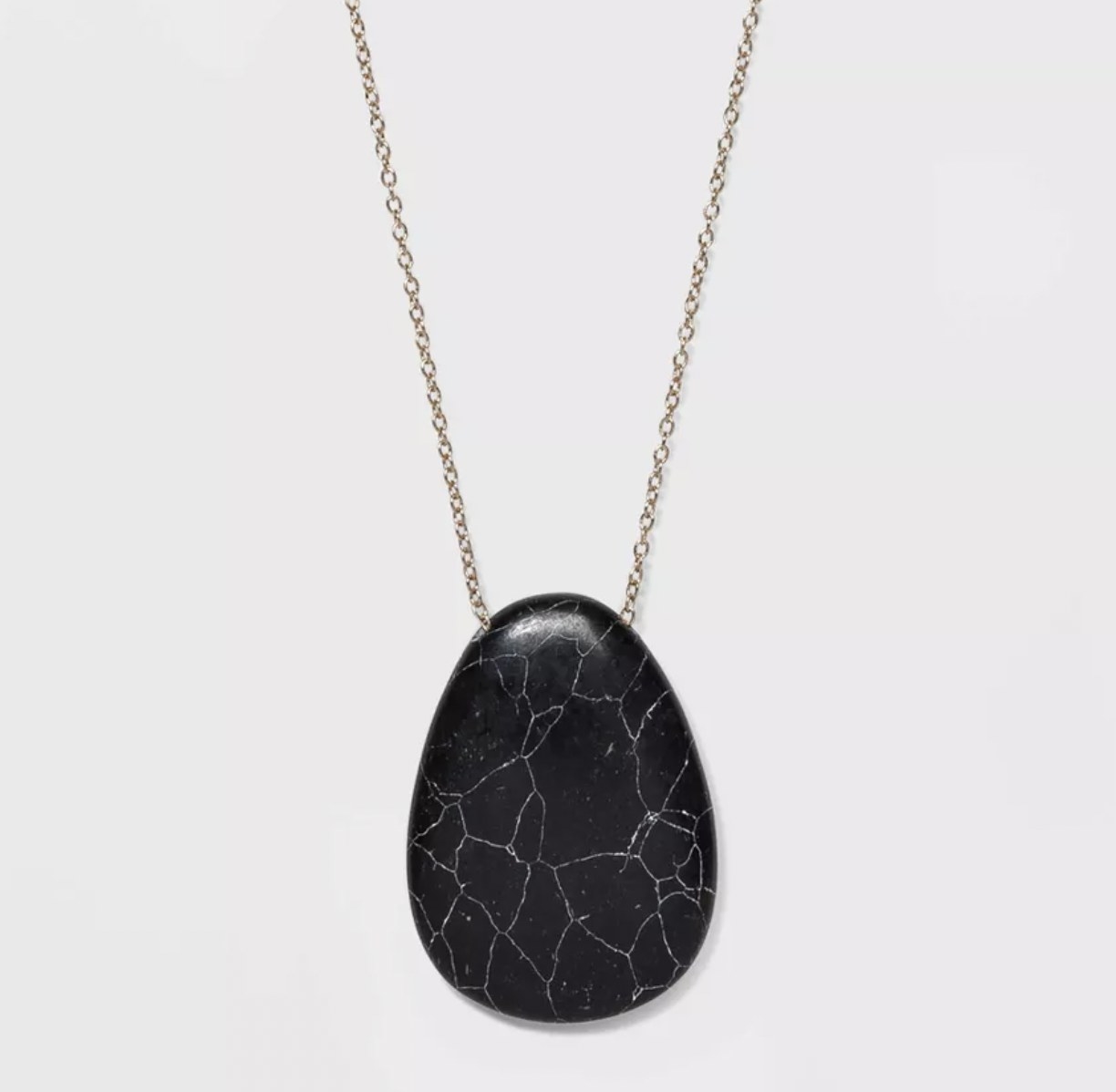 the black howlite pendant on a metal chain