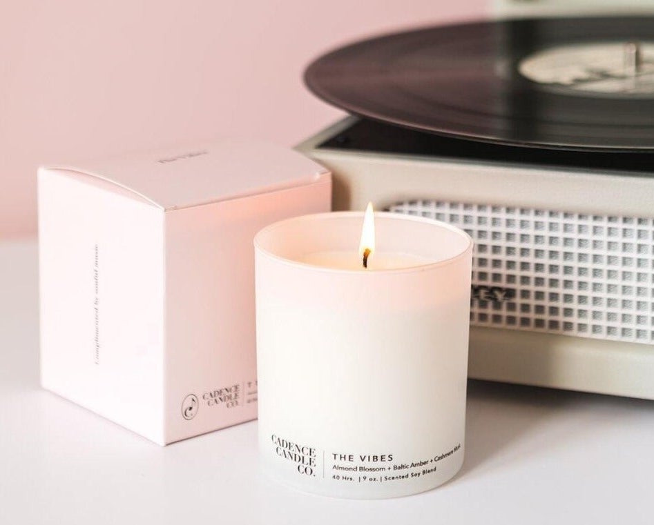 a white candle that says &quot;the vibes&quot; next to a pink box