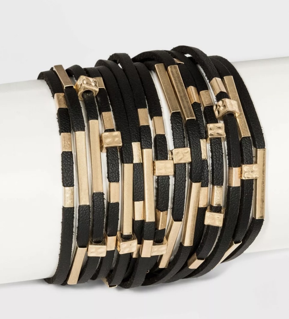 a black simulated wrap around bracelet with gold hardware.