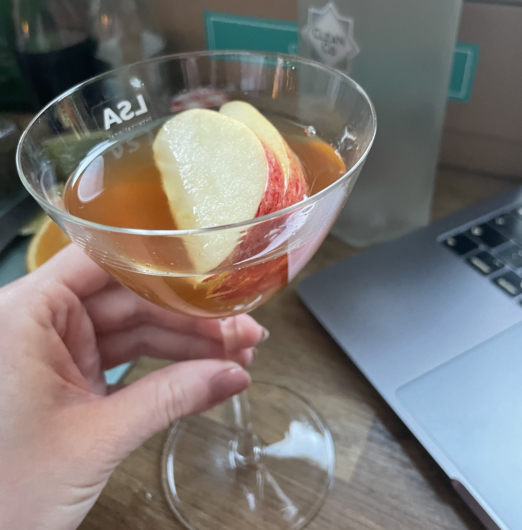 a completed martini in a tall martini glass with three slices of apple sitting on top
