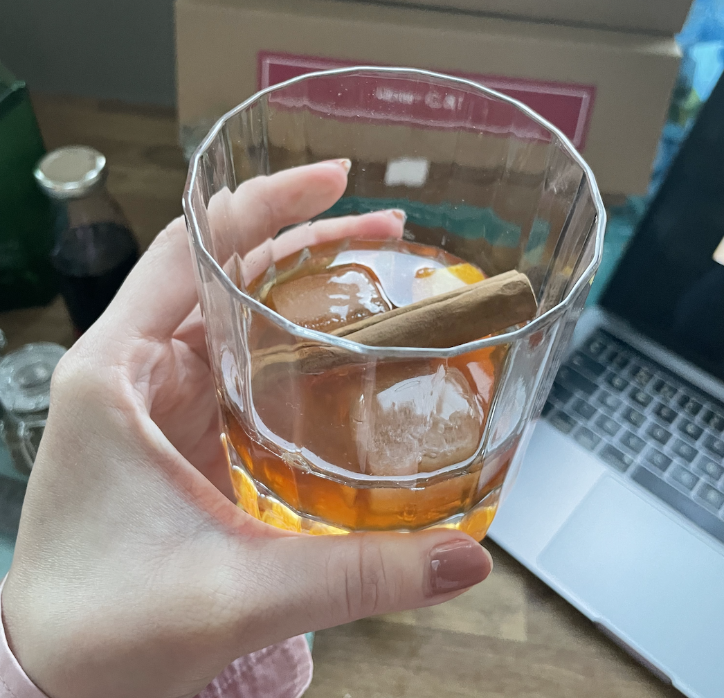 a completed marmalade rumfashioned in a short tumbler glass with ice and a cinnamon stick sitting in the drink