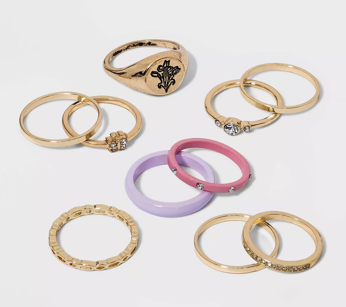 a set of gold-colored rings with gems, a signet ring, and a purple and pink enamel ring