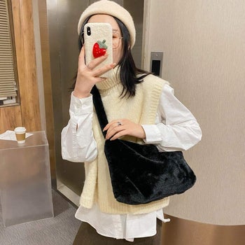 A model taking a selfie while wearing the black purse as a crossbody