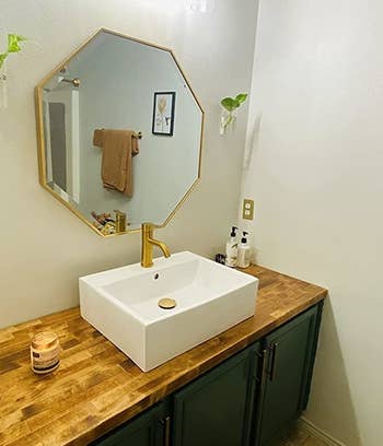reviewer photo of the gold mirror hanging above a bathroom sink