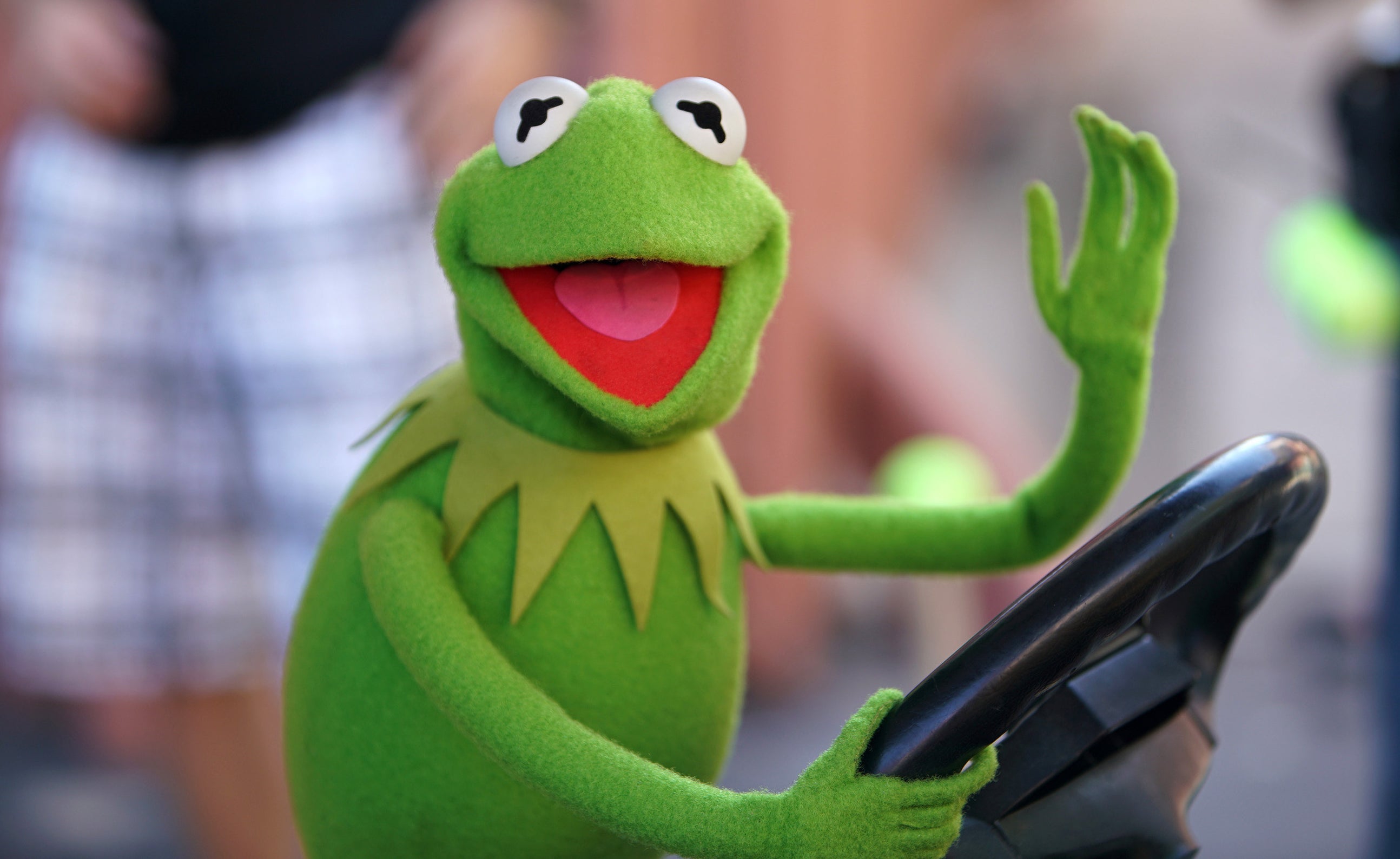 Kermit at the wheel waving and smiling