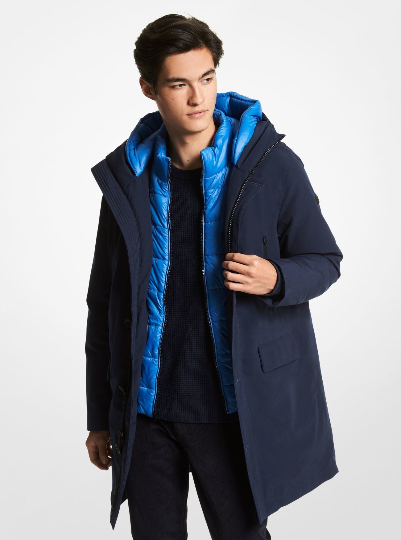 Model wearing a long navy coat with a lighter blue quilted lining