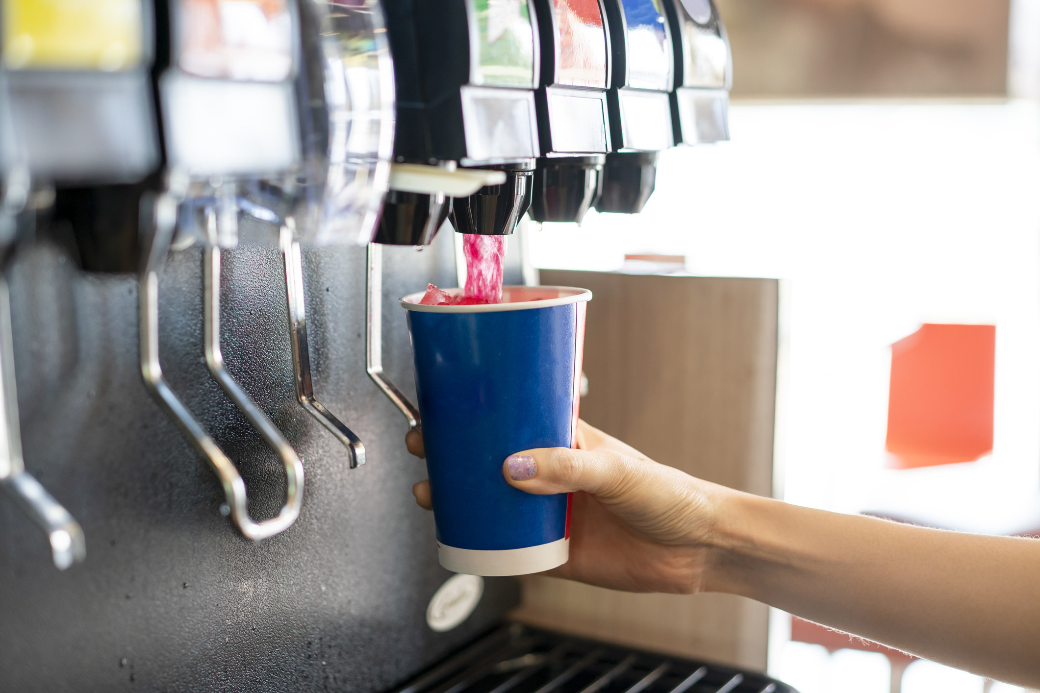 A man pouring a drink from a soda machine.