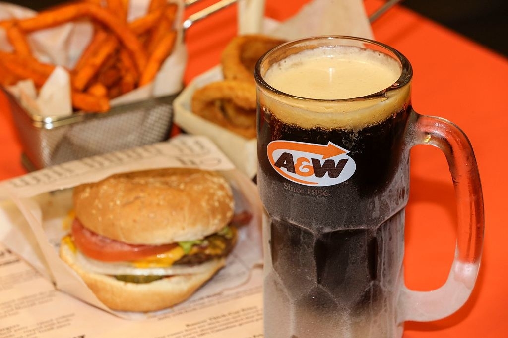 A glass of root beer and a burger.