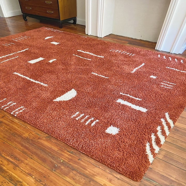 buzzfeed shopping writer britt ross' photo of the rust colored rug on her living room floor