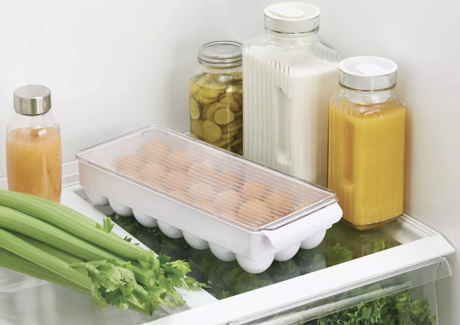 the egg organizer in a fridge surrounded by produce and drinks