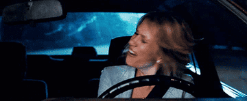 A woman swinging her hair back and forth while driving.