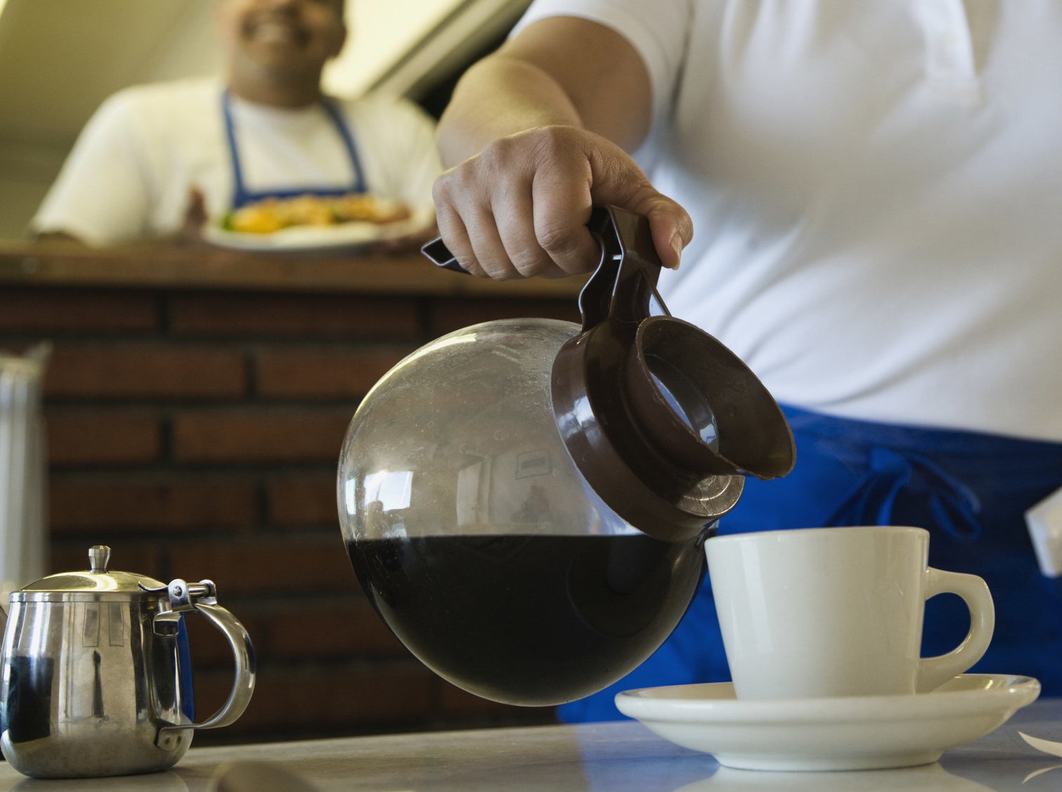 A server pouring a cup of coffee.