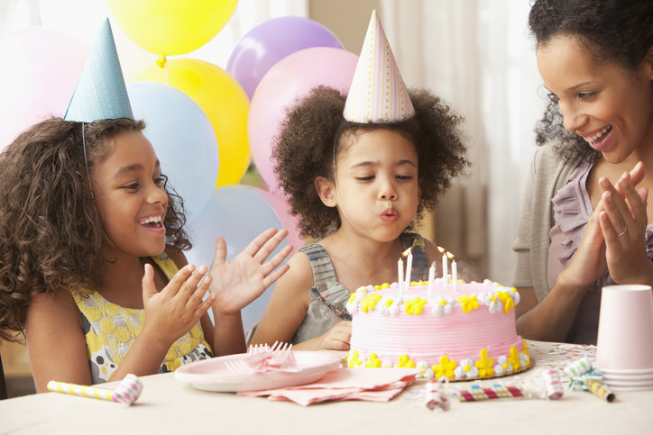 Child blowing out candles on birthday cake