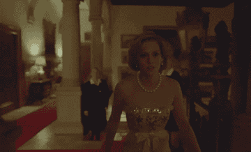 Kirsten as Princess Diana walking through a hallway