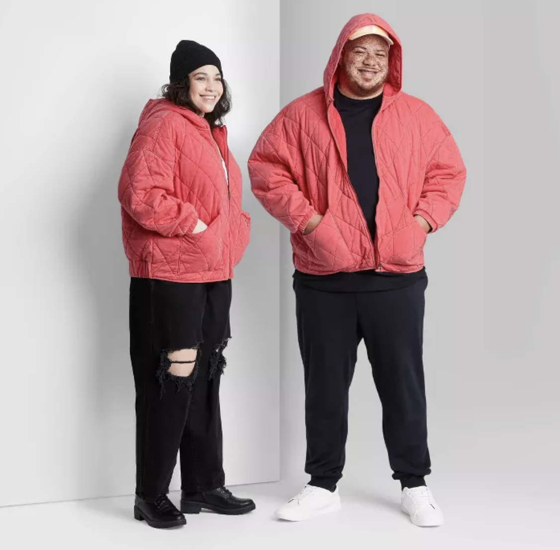 Two models wearing coral quilted jacket with hood and black pants