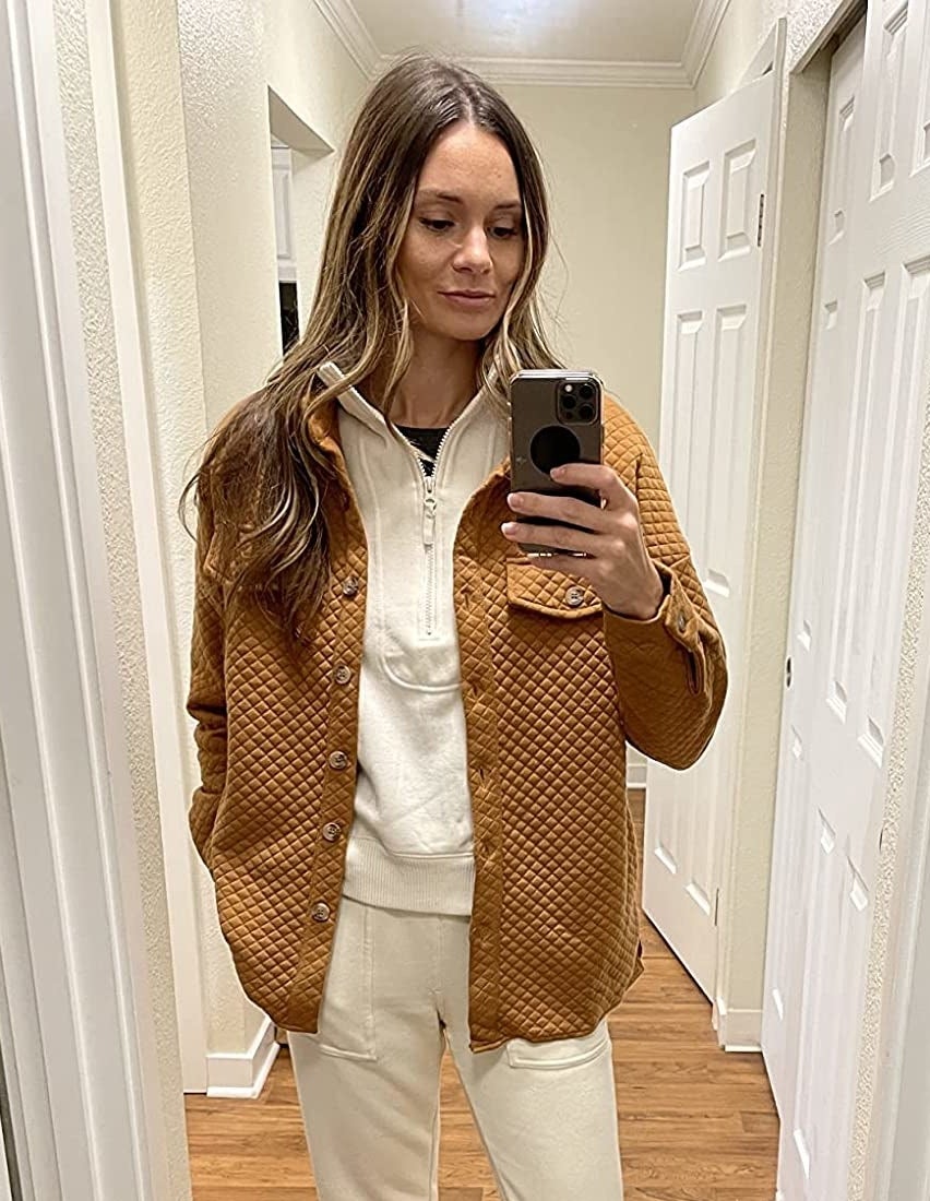 Reviewer wearing brown button-down quilted jacket with white sweats and a sweatshirt