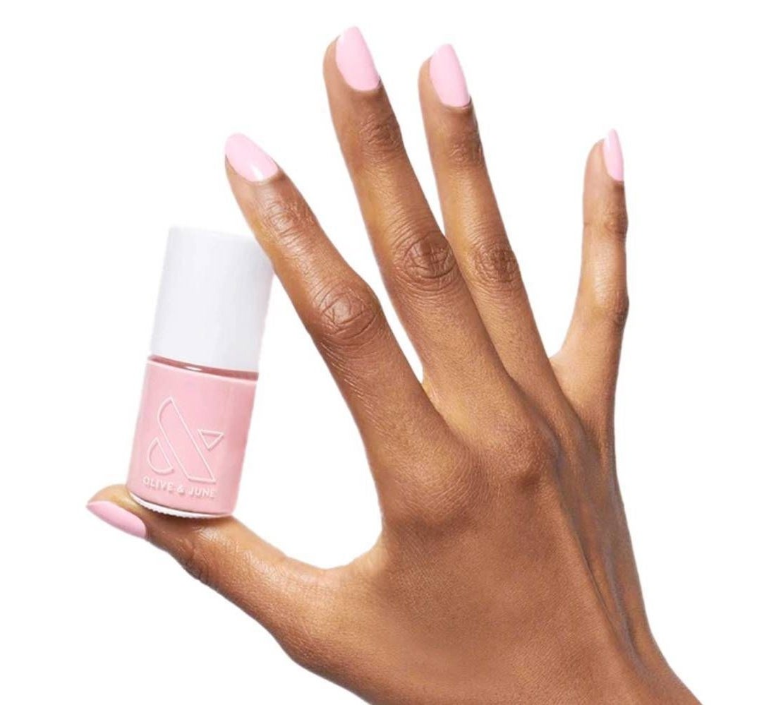 A hand holding a pink nail polish