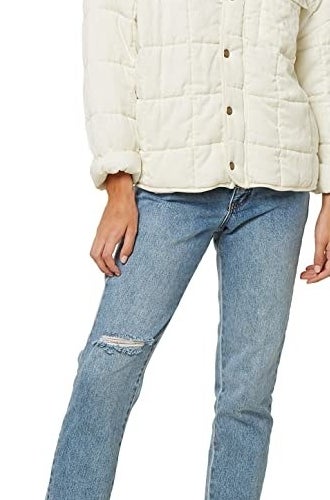 Model wearing white relaxed-fit quilted jacket with sleeves rolled up and tennis shoes