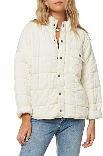Model wearing white relaxed-fit quilted jacket with sleeves rolled up and tennis shoes