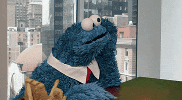 Cookie Monster tapping his fingers bored on a table