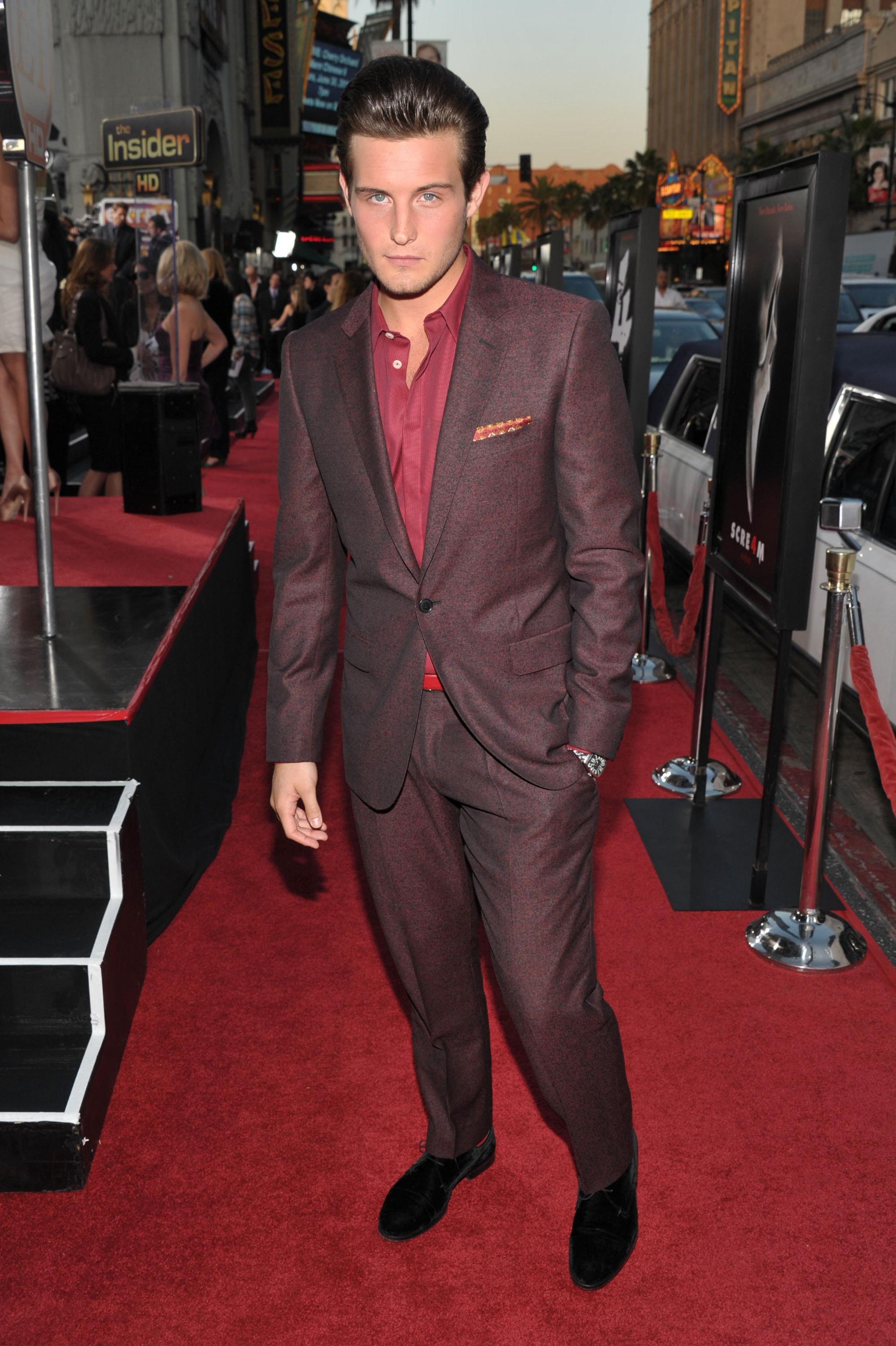 Nico Tortorella in a maroon suit with a red collared shirt