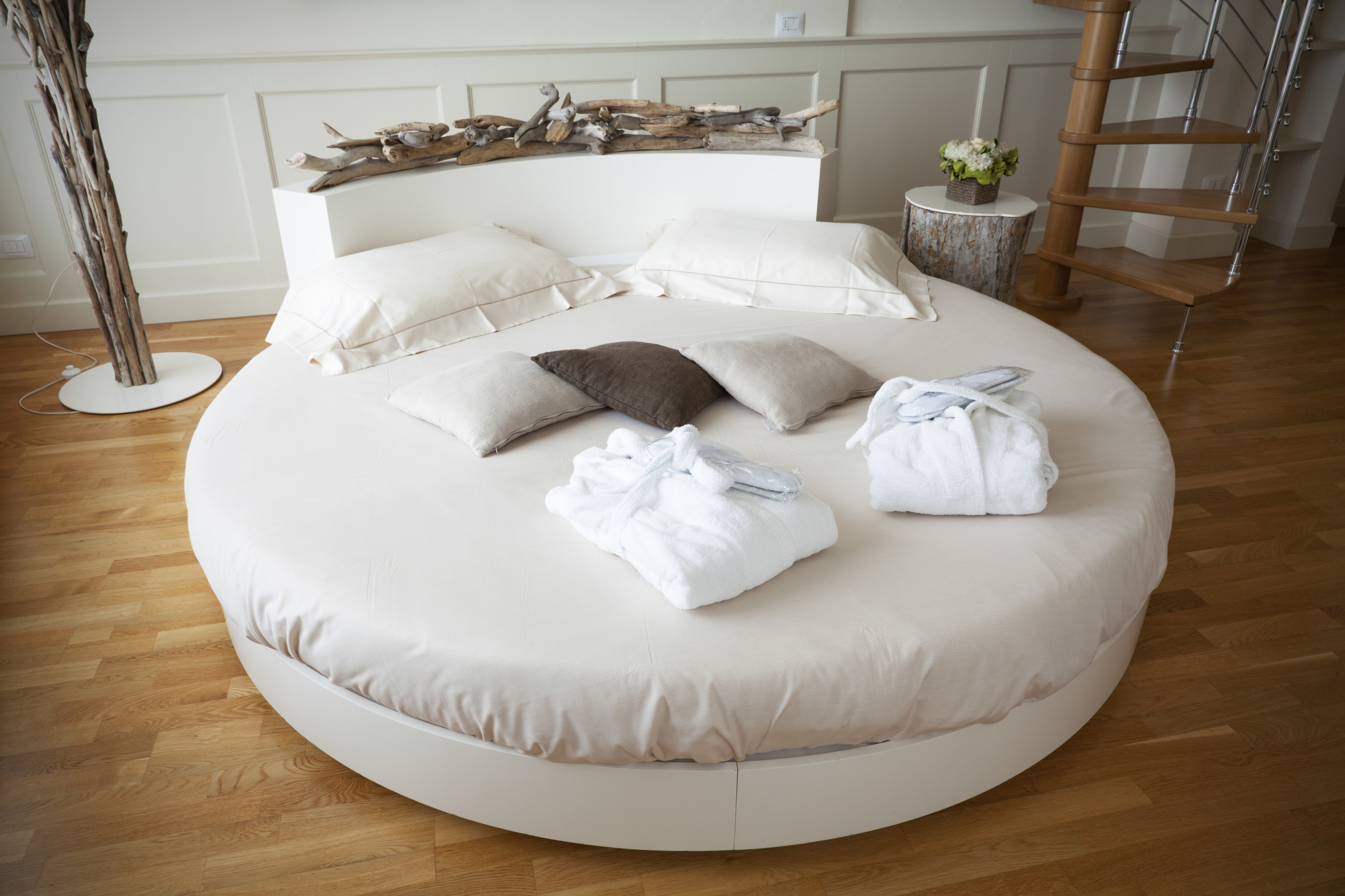 A circular white bed on a timber floor in a modern home