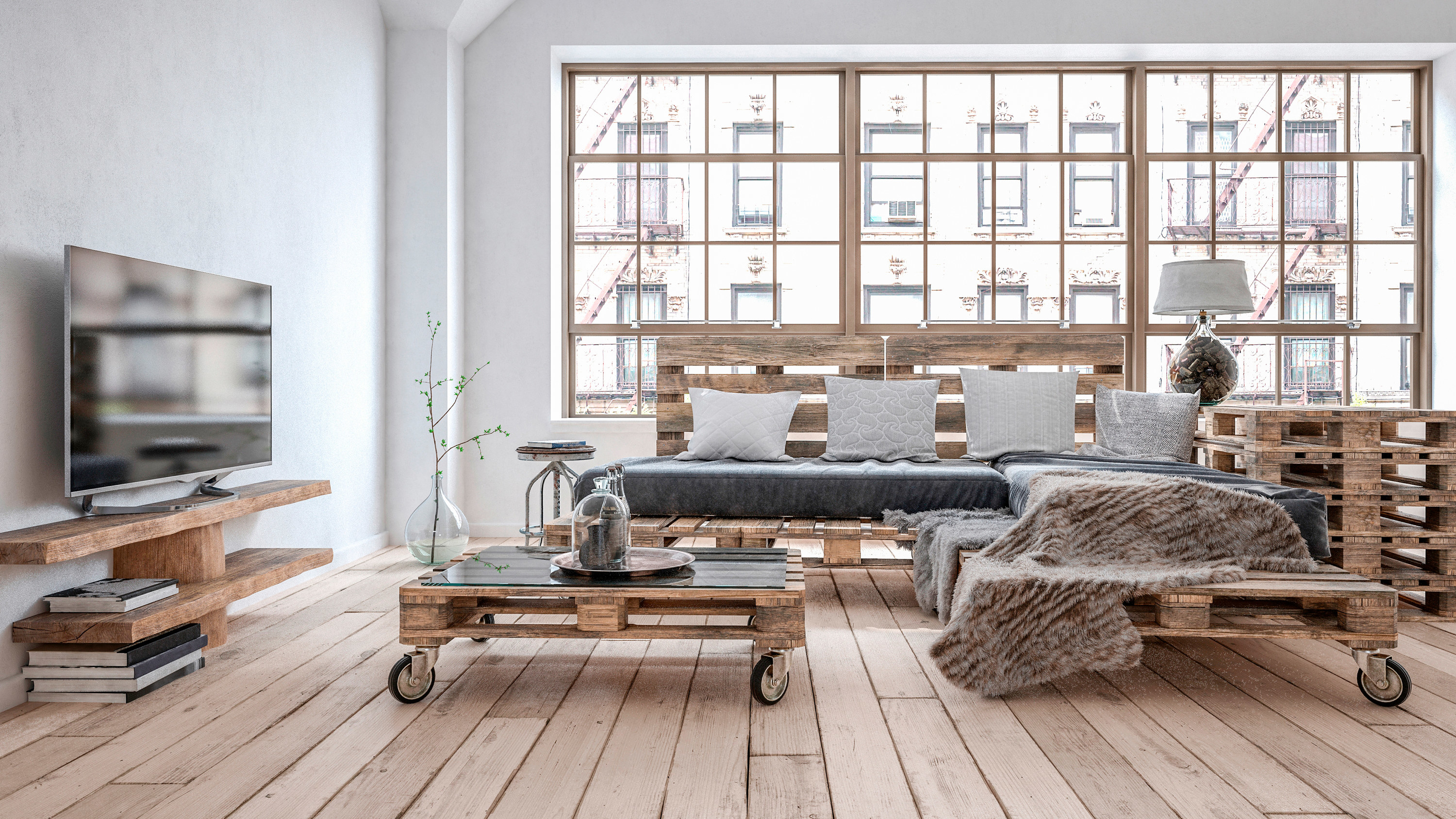 A living room with timber floors, big warehouse windows - all the furniture including sofa, table, end table, and shelves are made from wooden pallets