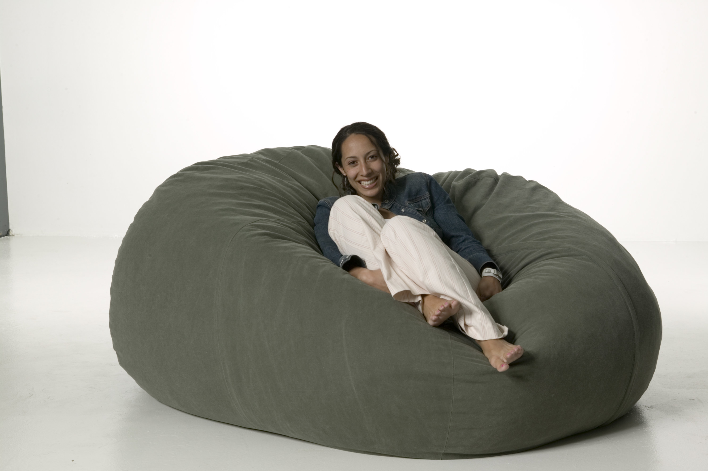 A girl sits in a big round bean bag cushion chair