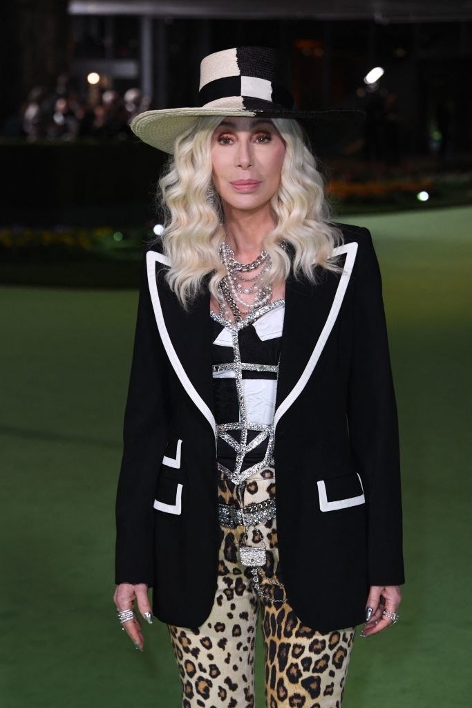 Cher has light blonde hair and leopard print leggings