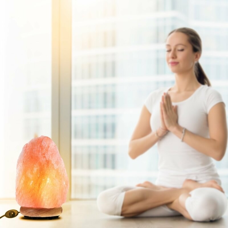 The salt lamp glowing next to a woman meditating