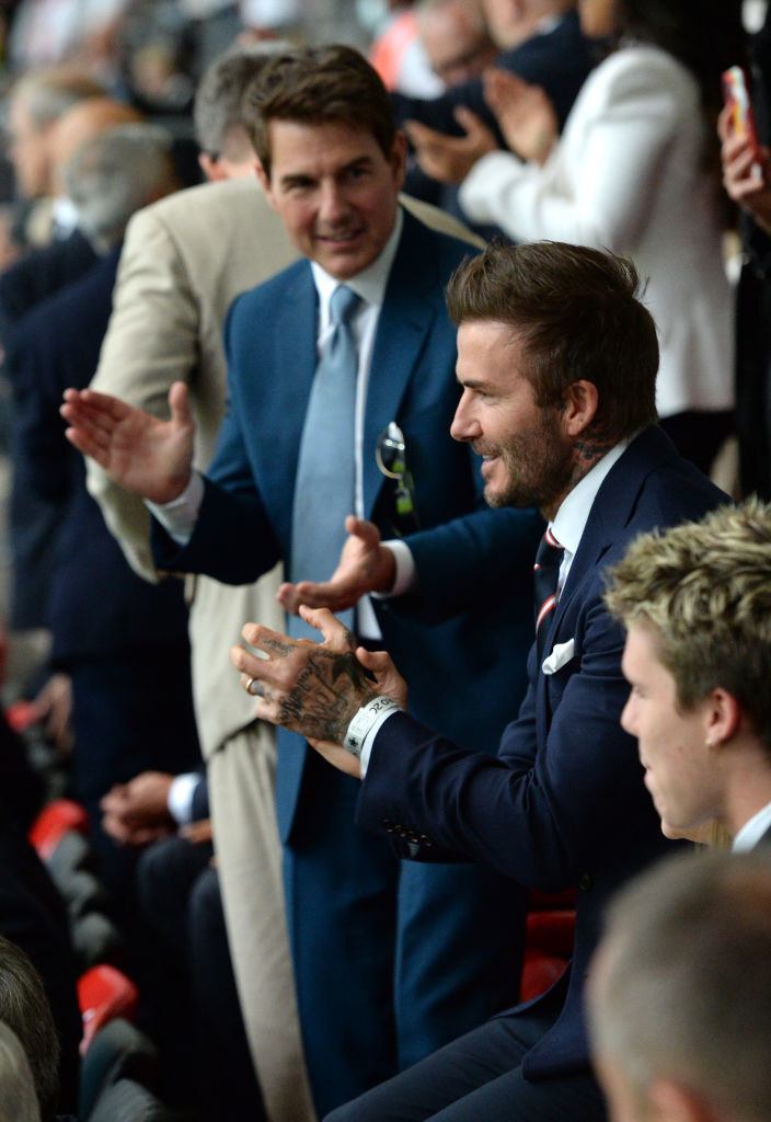 Tom is clapping with David Beckham at a soccer game