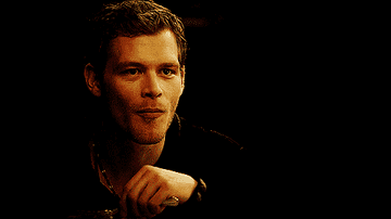 Klaus putting his finger to his mouth in a hushing motion