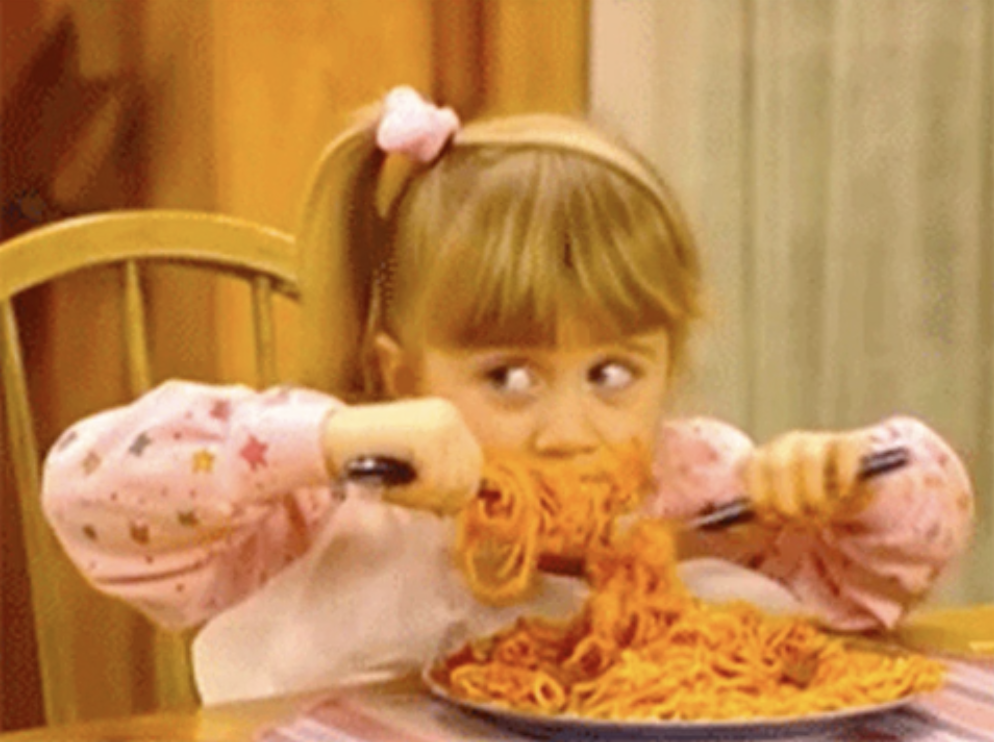 A young girl eats a mouthful of pasta.