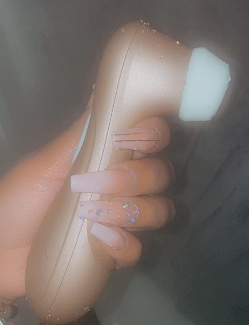 Model holding rose gold sex toy in shower