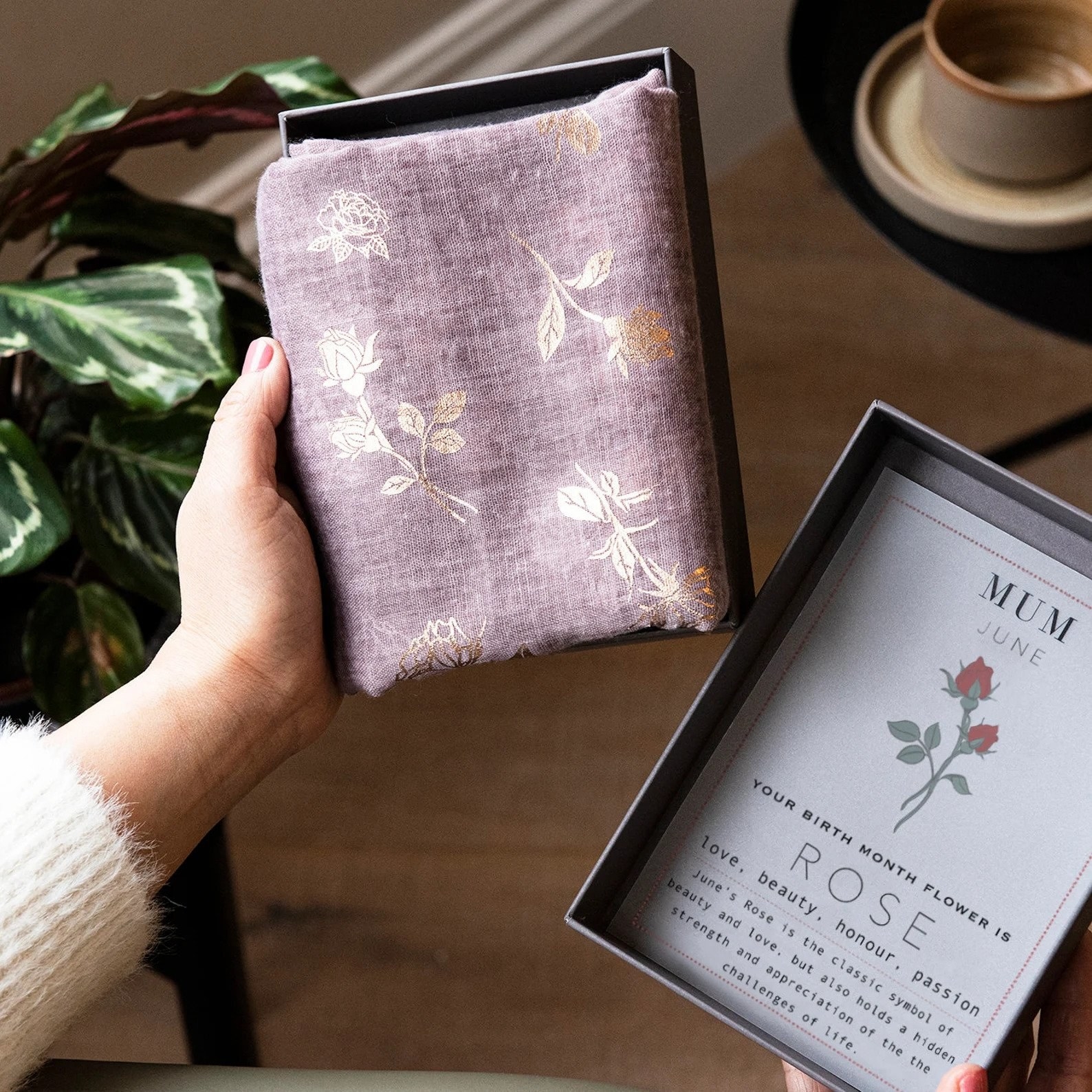 closeup of a purple linen scarf with gold rose details in a box for the birth month of june