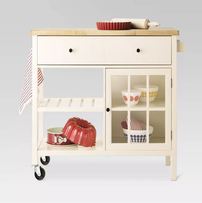 an off white bar cart with other kitchen essentials tucked into drawers and shelves