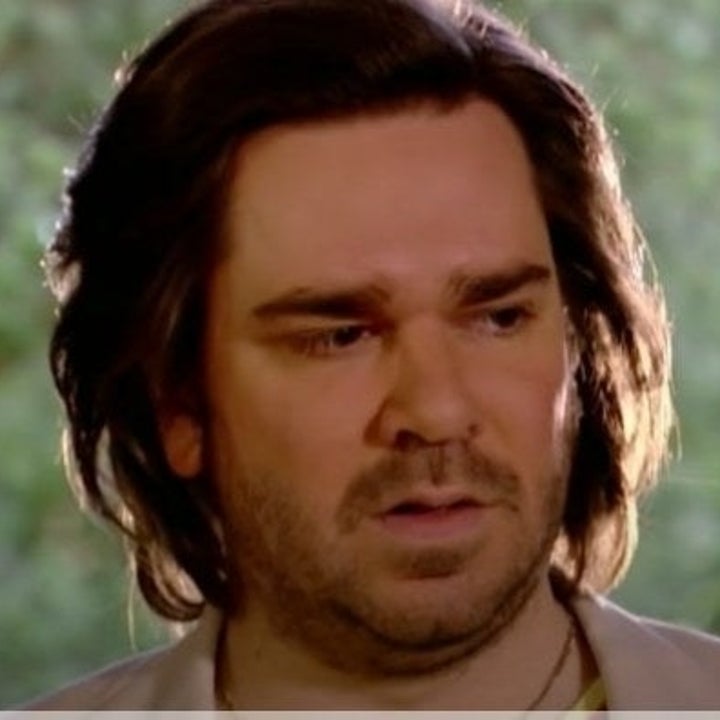 Matt Berry looks toward an audience with trees behind him
