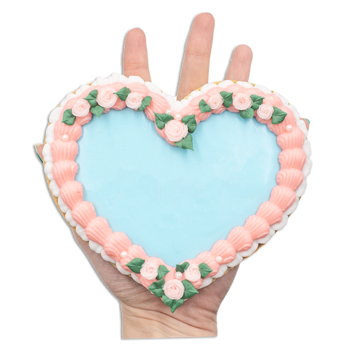 a heart-shaped cookie with pink piping around it and blue frosting in the middle