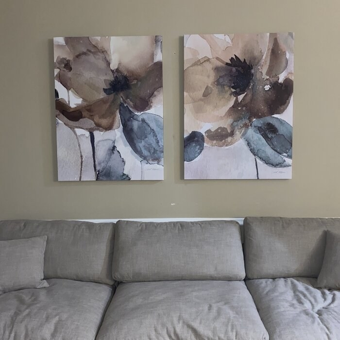 A reviewer&#x27;s photo of two of the poppy canvases hanging above her couch