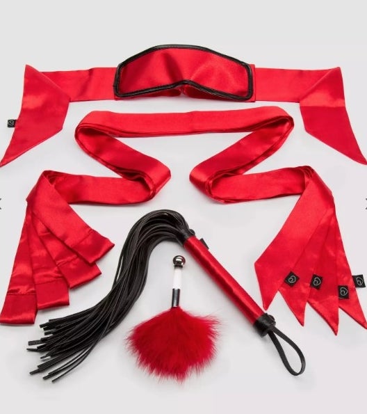 A red/black bondage kit with one blindfold, one flogger, one feather tickler, and four satin restraints