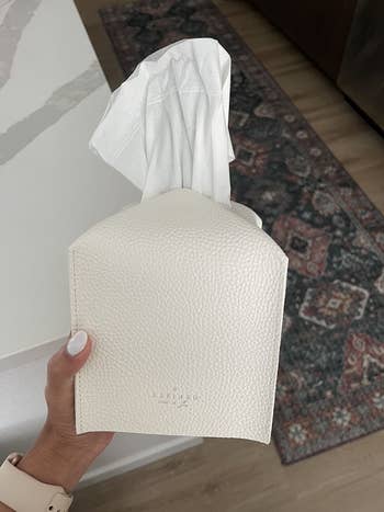 a reviewer holding a white faux leather tissue box cover