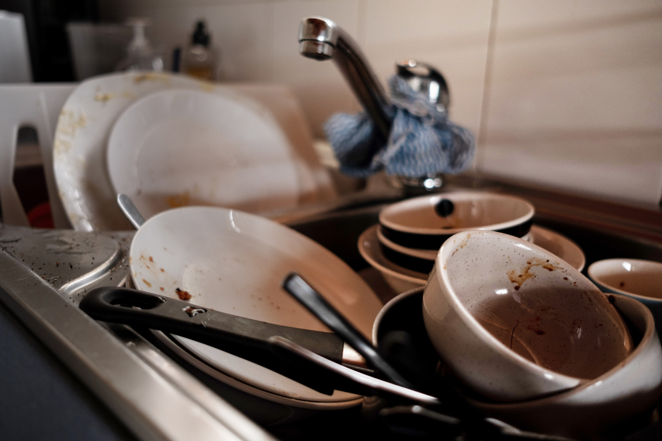 A pile of unwashed dishes stacked in a kitchen sink.