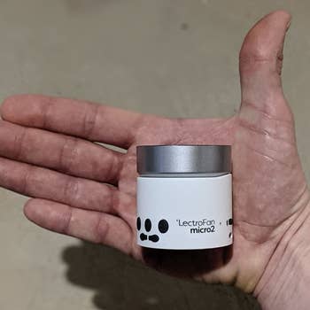 a reviewer holding a small white noise machine in the palm of their hand