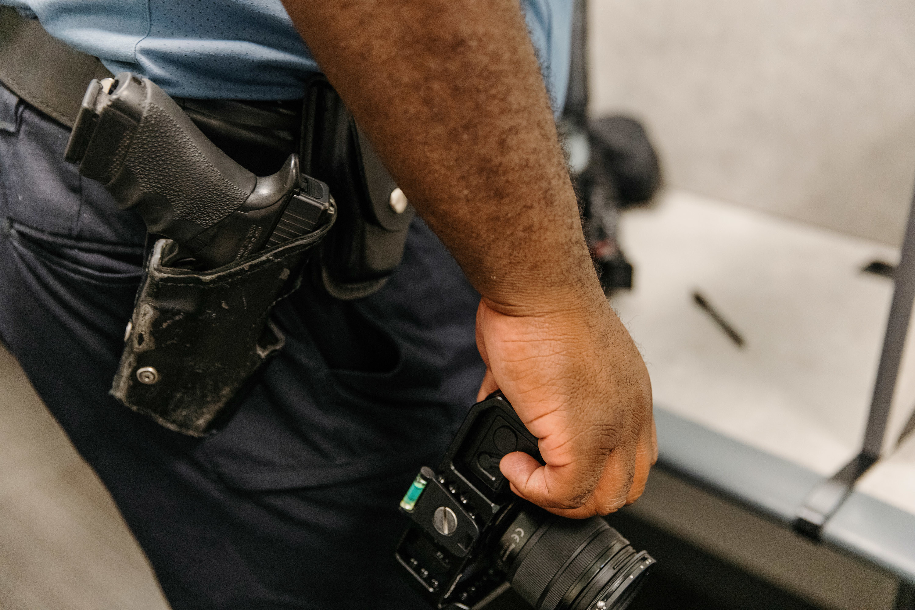 A police officer holds a digital camera near the gun holster on his waist