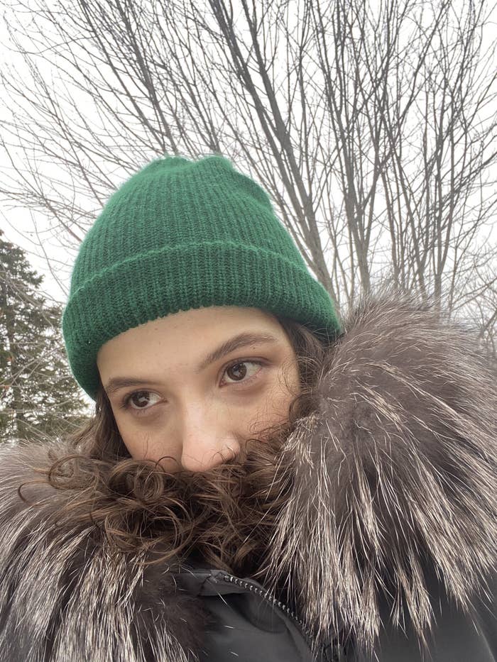 er Maya Ogolini stands outside and covers the bottom of her face with the top of her winter jacket